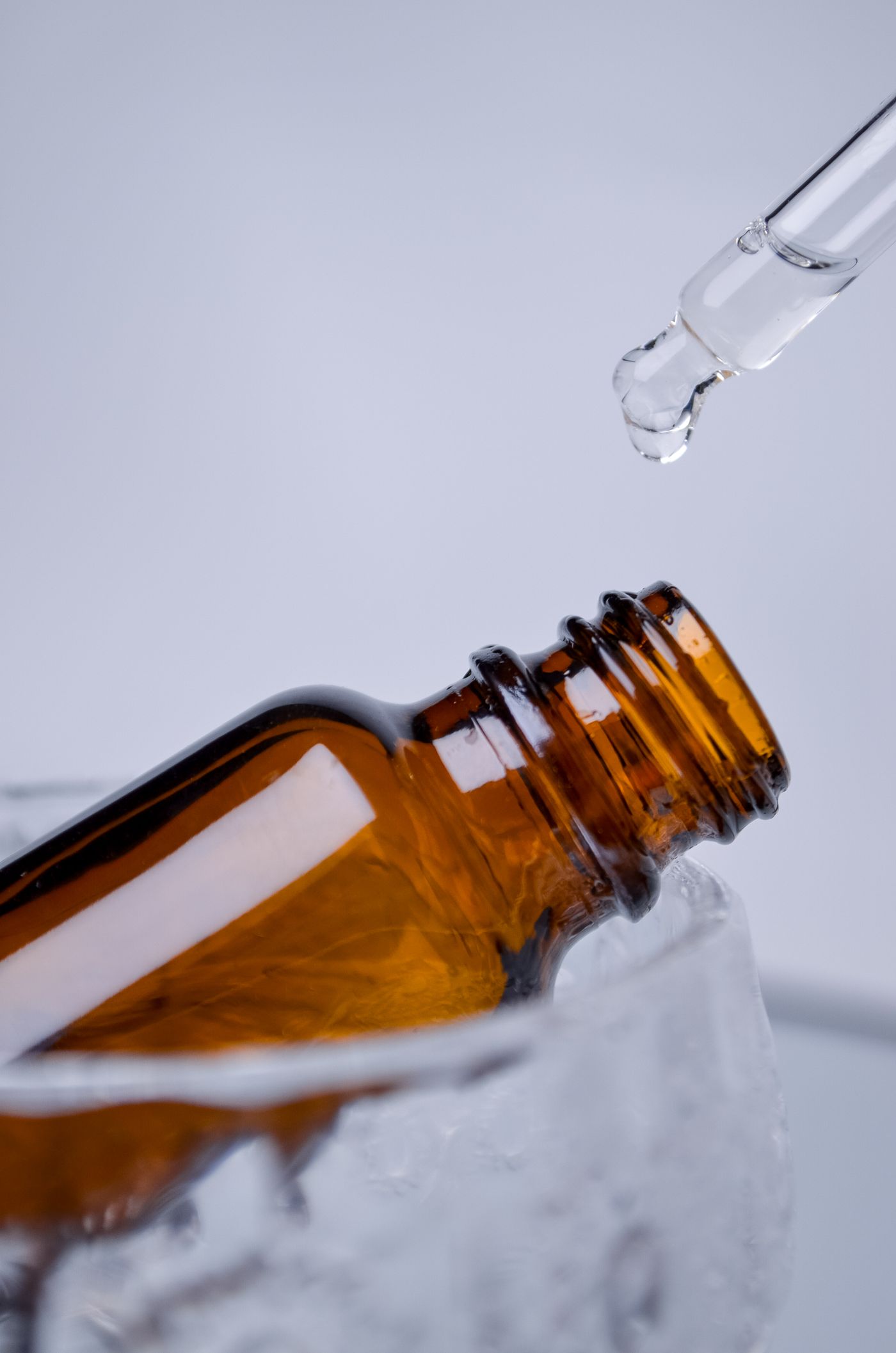 Tetesan cairan dari pipet di atas botol kaca cokelat